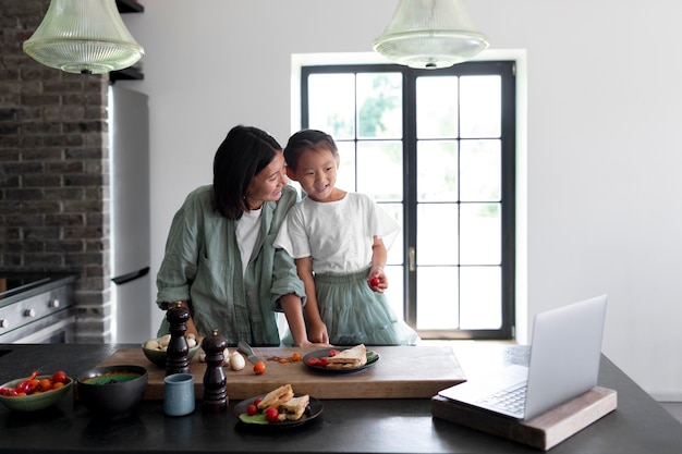 Mère et fille ayant un appel vidéo depuis leur cuisine