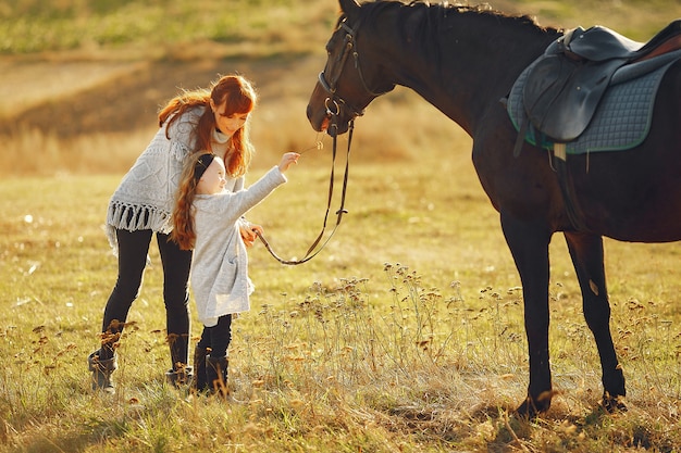 Mère et fille dans un champ jouant avec un cheval