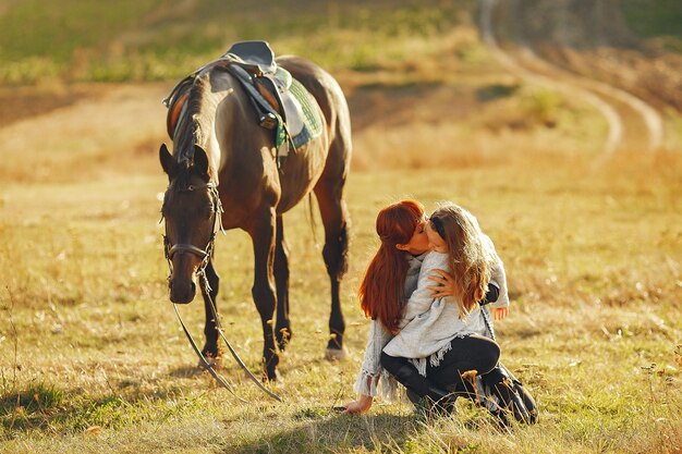 Mère et fille dans un champ jouant avec un cheval