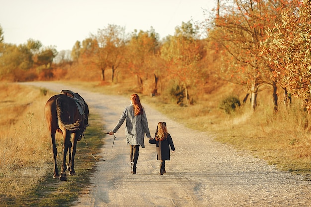 Photo gratuite mère et fille dans un champ jouant avec un cheval