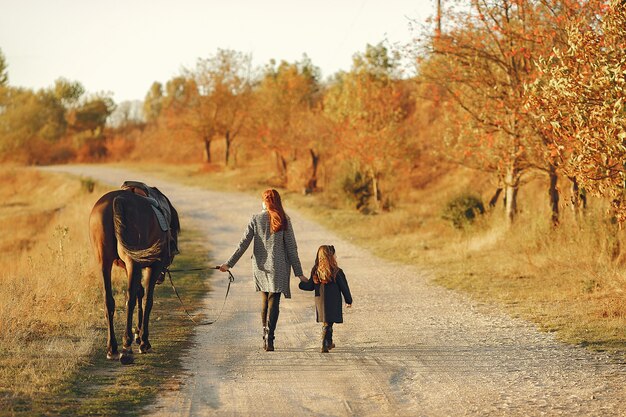 Mère et fille dans un champ jouant avec un cheval