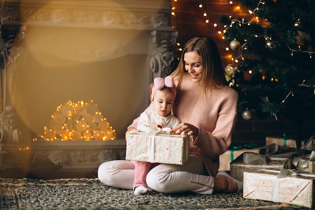 Mère avec fille déballer des cadeaux de Noël par sapin de Noël