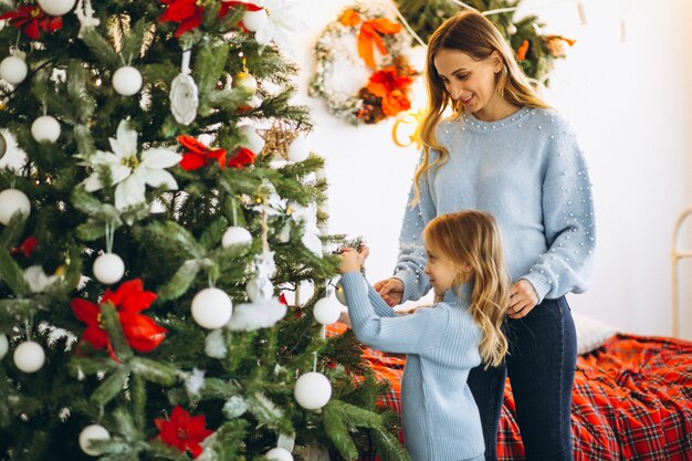 Mère avec fille décorer un arbre de Noël