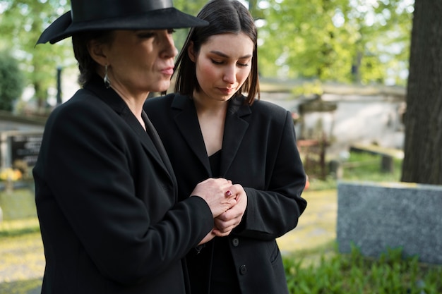 Photo gratuite mère et fille en deuil sur une tombe du cimetière