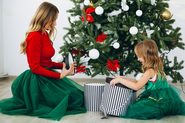 Mère avec fille emballer des cadeaux par sapin de Noël