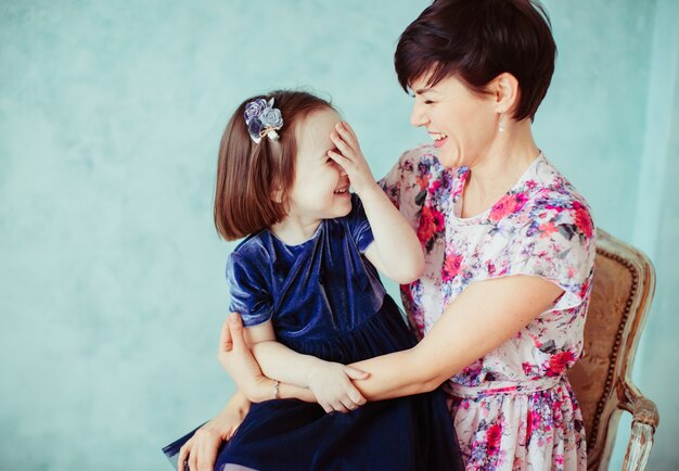 La mère avec la fille embrassant et assis sur la chaise