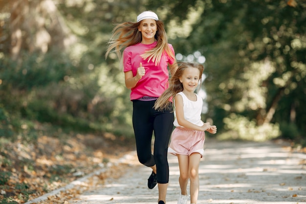 Mère avec fille faire du sport dans un parc d'été