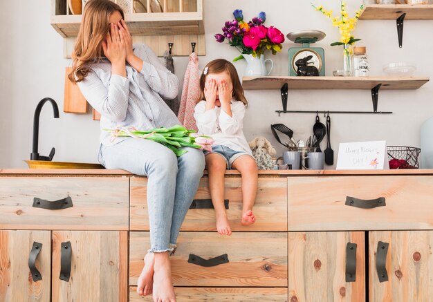 Mère et fille avec des fleurs de tulipes couvrant les yeux