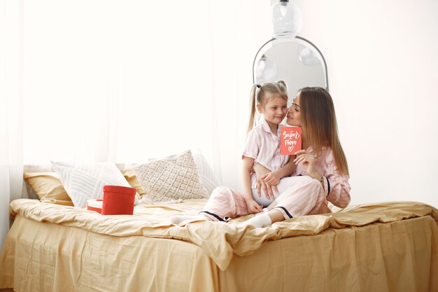 Mère et fille jouissant sur le lit. Tenant une boîte cadeau rouge. Fête des mères.