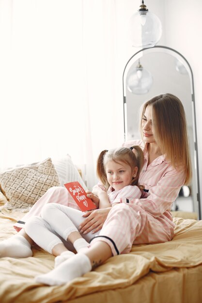 Mère et fille jouissant sur le lit. Tenant une boîte cadeau rouge. Fête des mères.