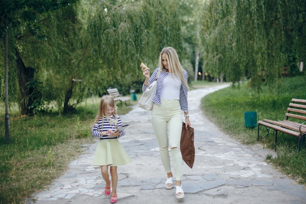 Mère et fille marchant dans un parc avec un téléphone et une tablette