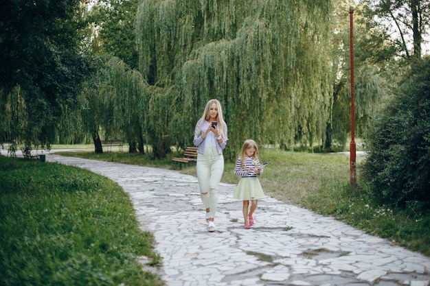 Mère et fille avec un mobile et une tablette marchant dans un parc