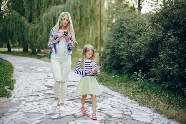 Mère et fille avec un mobile et une tablette marchant dans un parc