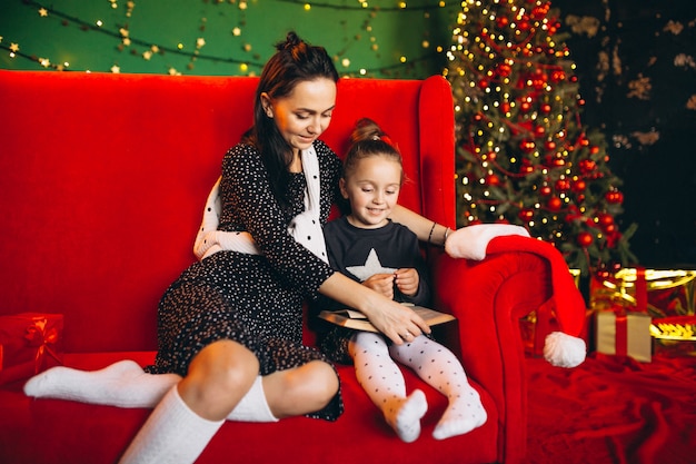 Mère avec fille à Noël assis sur un canapé avec des cadeaux