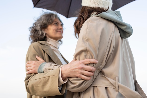 Photo gratuite mère et fille partageant un moment de tendresse sur la plage sous un parasol