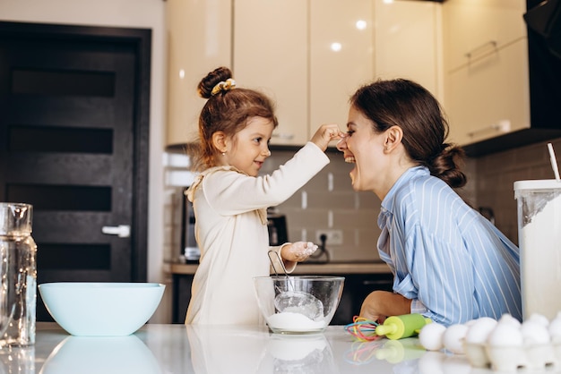 Mère avec fille s'amusant avec de la farine à la cuisine