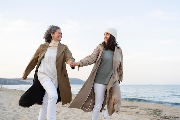 Photo gratuite mère et fille se tenant la main à la plage ensemble