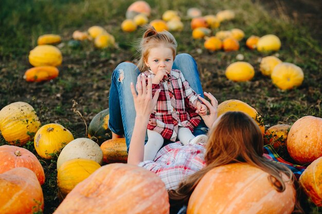 Mère et fille se trouvent entre les citrouilles sur le terrain