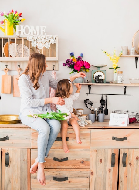 Photo gratuite mère et fille avec des tulipes assis sur une table