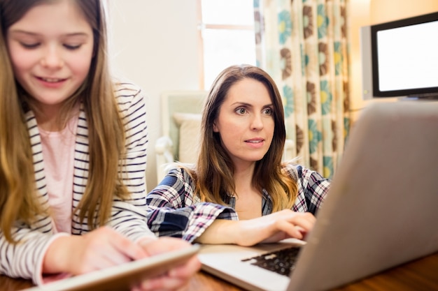 Mère et fille utilisant un ordinateur portable et tablette numérique