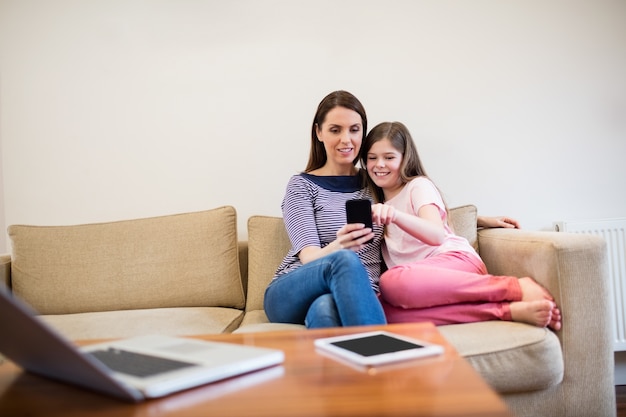 Mère et fille utilisant portable dans le salon