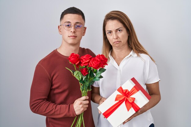 Mère et fils tenant un cadeau de fête des mères détendu avec une expression sérieuse sur le visage. simple et naturel en regardant la caméra.