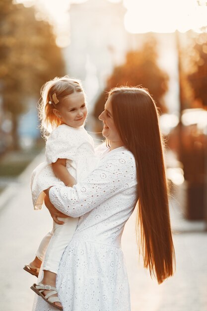 Mère avec gaughter jouant. Femme en robe blanche. Famille sur fond de coucher de soleil.