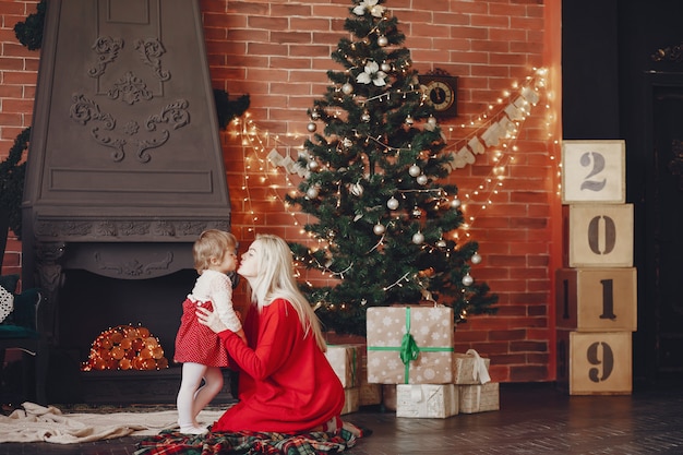 Mère avec jolie fille à la maison dans une robe rouge