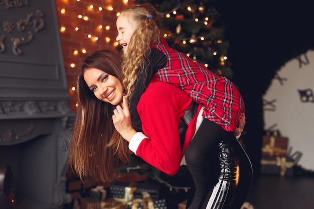 Mère avec jolie fille à la maison près de cheminée