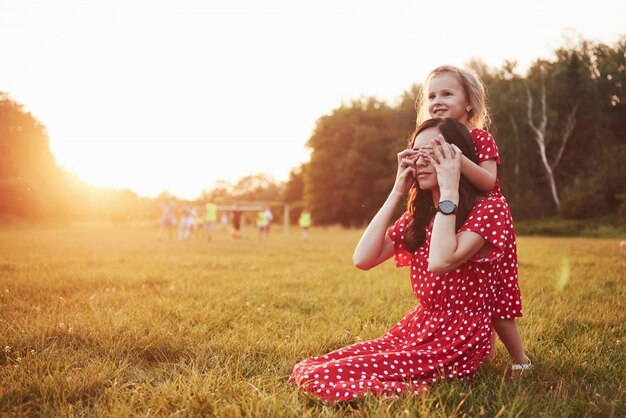 Mère joue avec sa fille dans la rue dans le parc au coucher du soleil