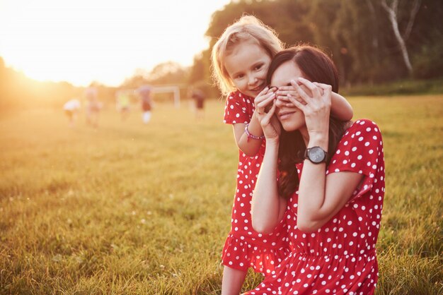 Mère joue avec sa fille dans la rue dans le parc au coucher du soleil