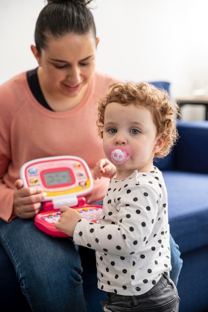 Mère à la maison assise sur le canapé et jouant avec l'enfant