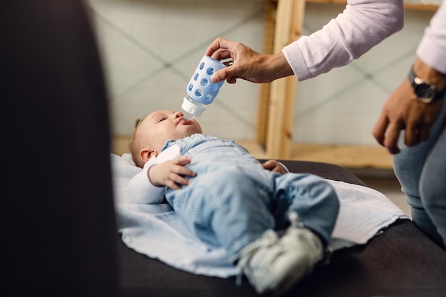 Mère méconnaissable nourrissant son petit garçon allongé sur le canapé