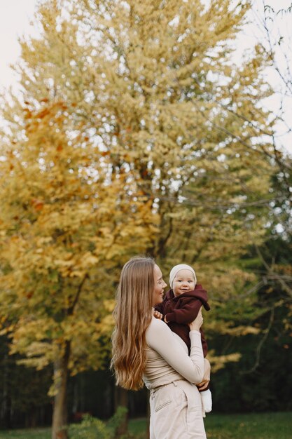 Mère à la mode avec sa fille. Les gens marchent dehors. Femme dans un pull marron.