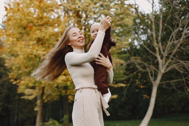 Mère à la mode avec sa fille. Les gens marchent dehors. Femme dans un pull marron.