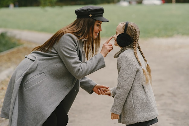 Photo gratuite mère à la mode avec sa fille. les gens marchent dehors. femme en manteau gris.