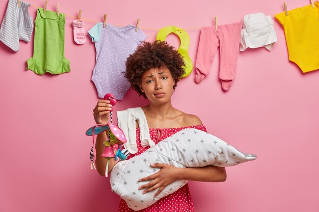 Une mère occupée allaite son bébé, passe des nuits blanches, embrasse son bébé enveloppé dans une couverture, tient son portable, épuisée après avoir lavé les vêtements des enfants, veut faire la sieste. Concept de maternité