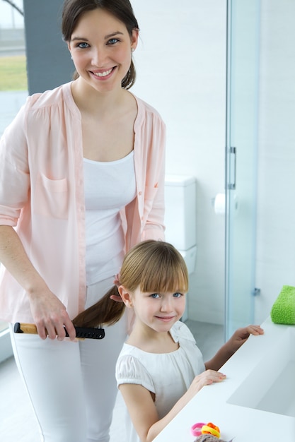 Mère peignant sa fille dans la salle de bain