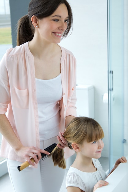 Mère peignant sa fille dans la salle de bain