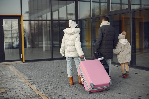 Mère père et fille avec bagages allant au terminal de l'aéroport