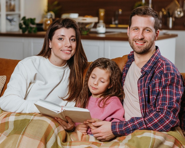 Mère et père lisant un livre à la maison avec sa fille