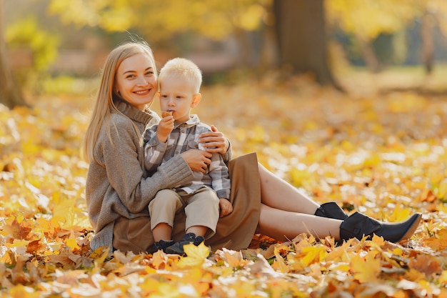 Mère avec petit fils assis dans un champ d'automne