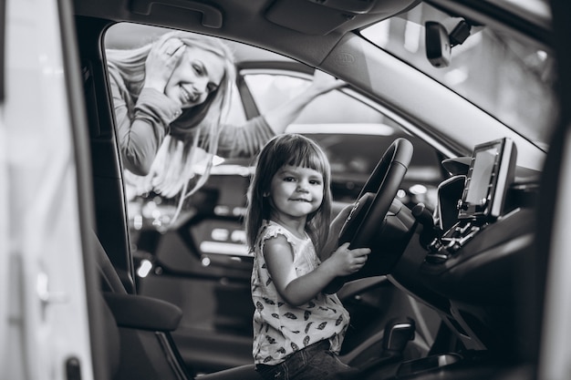 Mère avec petite fille assise dans une voiture dans une salle d'exposition