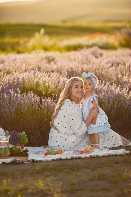 Mère avec petite fille sur champ de lavande. Belle femme et bébé mignon jouant dans le champ de prairie. Vacances en famille en journée d'été.