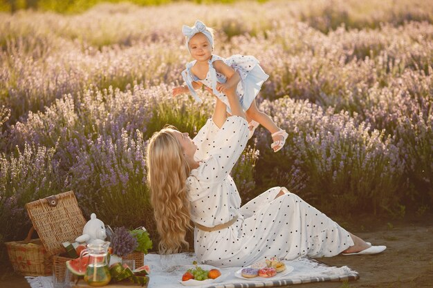 Mère avec petite fille sur champ de lavande. Belle femme et bébé mignon jouant dans le champ de prairie. Vacances en famille en journée d'été.