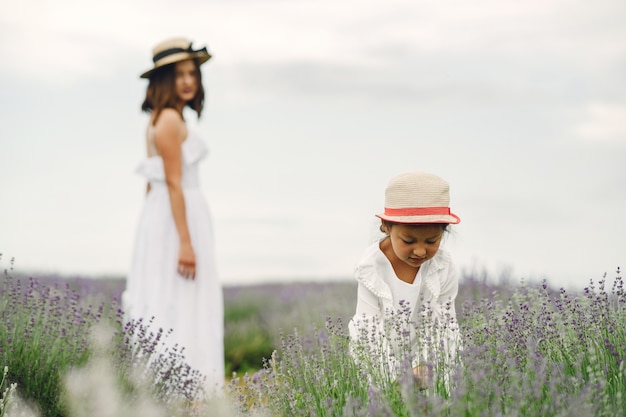 Mère avec petite fille sur champ de lavande. Belle femme et bébé mignon jouant dans le champ de prairie. Vacances en famille en journée d'été.