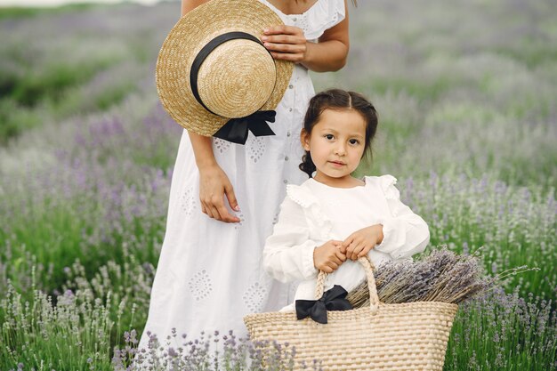 Mère avec petite fille sur champ de lavande. Belle femme et bébé mignon jouant dans le champ de prairie. Vacances en famille en journée d'été.