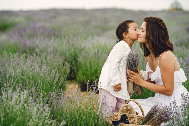 Mère avec petite fille sur champ de lavande. Belle femme et bébé mignon jouant dans le champ de prairie. Vacances en famille en journée d'été.