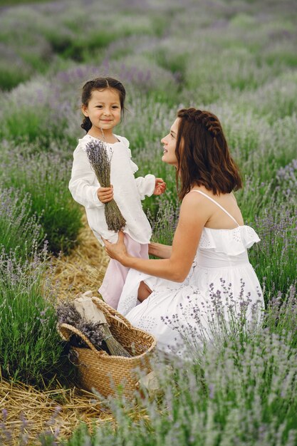 Mère avec petite fille sur champ de lavande. Belle femme et bébé mignon jouant dans le champ de prairie. Vacances en famille en journée d'été.