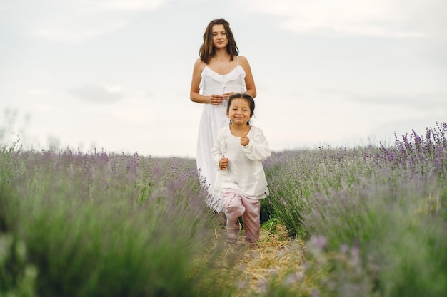 Mère avec petite fille sur champ de lavande. Belle femme et bébé mignon jouant dans le champ de prairie. Vacances en famille en journée d'été.